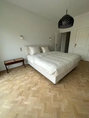 a bedroom with a white bed and a wooden floor at Cosy apartment with park view in Ghent
