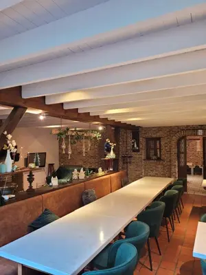 a long table in a restaurant with green chairs at Parkhoeve Vakantiewoning voor 21 personen in Ham
