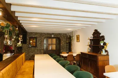 a restaurant with tables and chairs and a brick wall at Parkhoeve Vakantiewoning voor 21 personen in Ham
