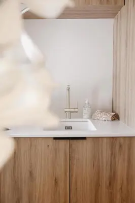 a white sink in a kitchen with wooden cabinets at The Millhouse in Sint-Niklaas