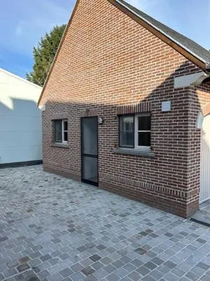 a brick building with a door and two windows at Duivenboshuisje in Herzele