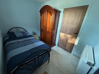 a bedroom with a bed and a wooden door at Duivenboshuisje in Herzele