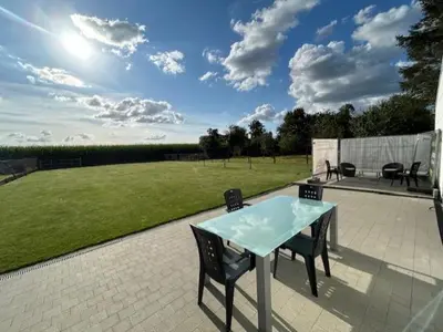 a patio with a table and chairs and a field at Duivenboshuisje in Herzele