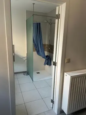 a bathroom with a shower with a blue shower curtain at Duivenboshuisje in Herzele