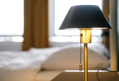 a lamp sitting on a table in front of a couch at Your homestay in a bibliophile mansion in Antwerp