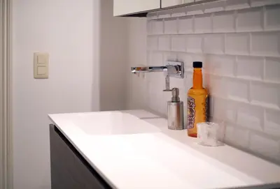 a kitchen counter with a sink and a bottle of alcohol at Your homestay in a bibliophile mansion in Antwerp