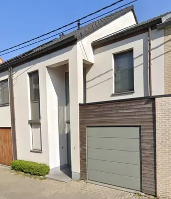 a white house with two garage doors on a street at Central Oasis near Brussels / Airport in Kortenberg
