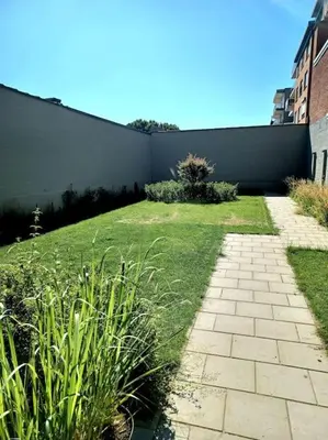 a grassy yard with a brick walkway next to a building at The Banker Antwerpen - Free Parking in Antwerp