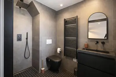 a bathroom with a black toilet and a sink at Cityview Modern Apartment with Balcony in Antwerp