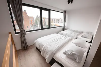 two beds in a small room with a window at K&Y suites 2 Brussels airport 500m! in Zaventem