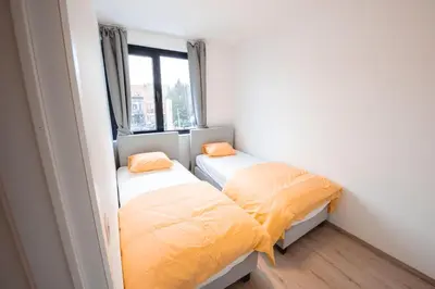 two beds in a small room with a window at K&Y suites 2 Brussels airport 500m! in Zaventem