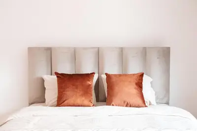 a white bed with two orange pillows on it at K&Y suites 3 Brussels airport 500m! in Zaventem