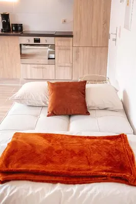 a large white bed with an orange blanket on it at K&Y suites 3 Brussels airport 500m! in Zaventem