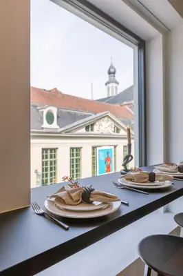 a table with plates and utensils and a large window at Margriet Apart-Suites in Ghent