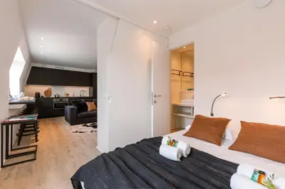 a bedroom with a large bed and a kitchen at Margriet Apart-Suites in Ghent