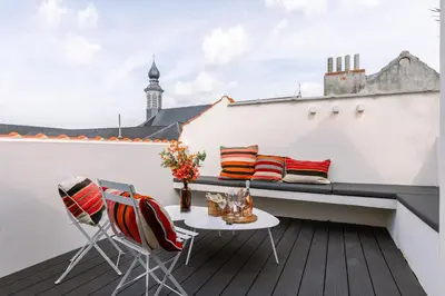 a balcony with a table and chairs on a white wall at Margriet Apart-Suites in Ghent