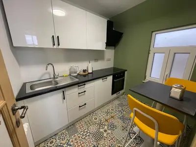 a kitchen with white cabinets and a sink and yellow chairs at Apartament duplex in Brussels