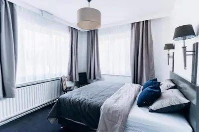 a bedroom with a bed with blue pillows and windows at Atomihotel: Contemporary Comfort Steps from the Atomium! in Brussels