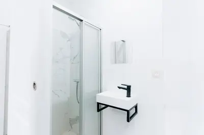 a white bathroom with a sink and a shower at Atomihotel: Contemporary Comfort Steps from the Atomium! in Brussels