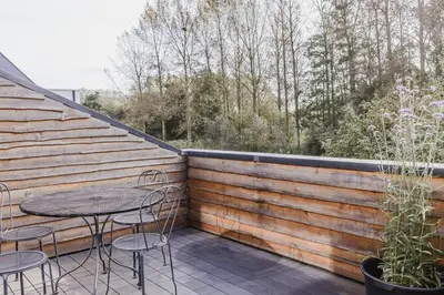 a patio with a table and chairs on a deck at ScraB&Ble Ecologische gastenkamers in Bornem