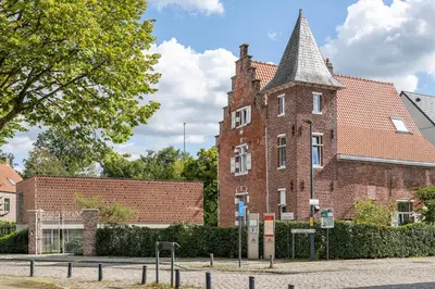 an old brick building with a tower on a street at B&B deZwarteFles in Ghent