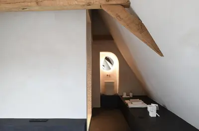 an attic bathroom with a white wall and wooden beams at B&B deZwarteFles in Ghent