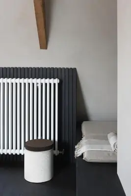 a room with a radiator and a stool and a table at B&B deZwarteFles in Ghent