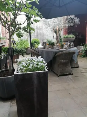a table in a garden with an umbrella and flowers at Casa della Nonna in Diest