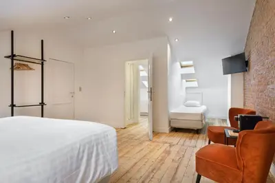 a bedroom with a white bed and a chair at The 1894 Boutique Holiday Apartment in Antwerp