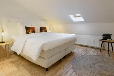 a bedroom with a large white bed and wooden floors at The 1894 Boutique Holiday Apartment in Antwerp