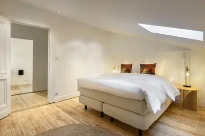 a white bedroom with a large bed and a skylight at Our Bird's Nest in the Heart of Antwerp in Antwerp