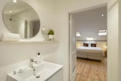 a bathroom with a sink and a mirror and a bed at Our Bird's Nest in the Heart of Antwerp in Antwerp