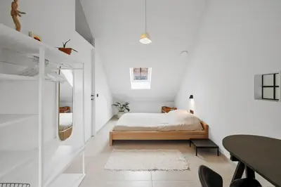 a white bedroom with a bed and a mirror at The barn - Waasmunster in Waasmunster