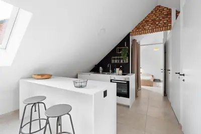 a kitchen with white counters and stools in a room at The barn - Waasmunster in Waasmunster