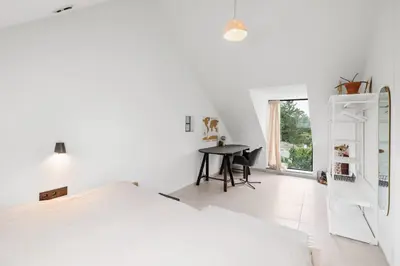 a white bedroom with a bed and a desk at The barn - Waasmunster in Waasmunster