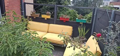 a yellow couch in a garden with potted plants at LodgeRivierenhof in Antwerp