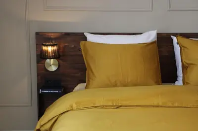 a bedroom with a yellow bed with a wooden headboard at Antwerp White House in Antwerp