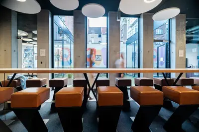 a restaurant with orange chairs and a table and windows at The ASH in Antwerp
