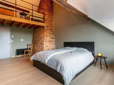 a bedroom with a large bed with a brick wall at Alverwege 2 in Merksplas