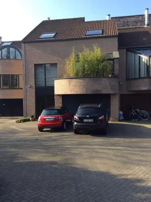 two cars parked in a parking lot in front of a building at B&B Uccle in Brussels