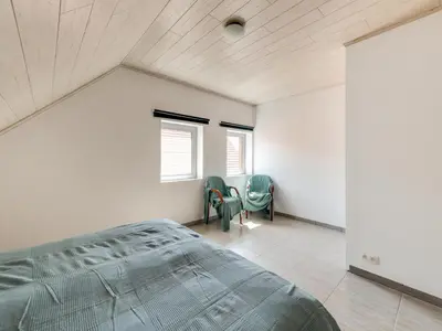 a bedroom with a bed and two chairs in it at In de Wollekjes in Merksplas