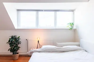 a white bedroom with a bed and a window at Guesthouse private studio nearby old town Ghent in Ghent