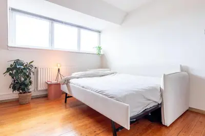 a white bedroom with a bed in a room with windows at Guesthouse private studio nearby old town Ghent in Ghent