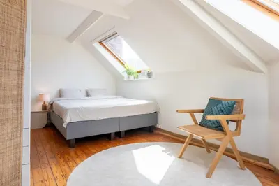 a bedroom with a bed and a chair in a attic at Guesthouse private studio nearby old town Ghent in Ghent