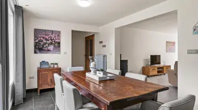 a dining room with a wooden table and white chairs at An's Vakantiehuisje in Dessel