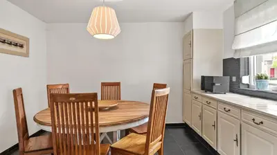 a dining room with a wooden table and chairs at An's Vakantiehuisje in Dessel