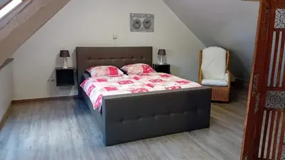 a bedroom with a bed and a chair in a attic at An's Vakantiehuisje in Dessel