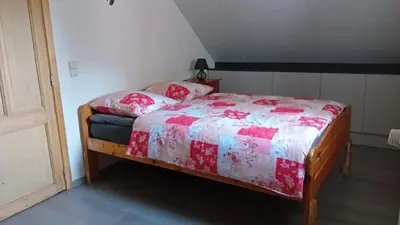 a bedroom with a bed with a red and white comforter at An's Vakantiehuisje in Dessel