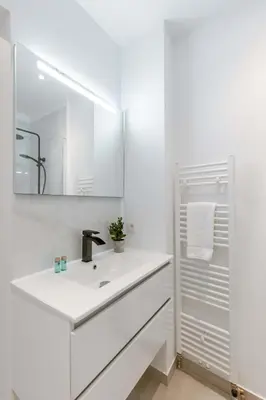a white bathroom with a sink and a mirror at Colorful POP apartment in the heart of Antwerp in Antwerp