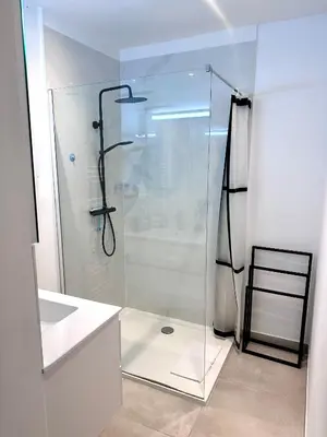 a glass shower in a white bathroom with a stool at Colorful POP apartment in the heart of Antwerp in Antwerp